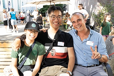 Zwei Männer und ein Kind sitzen auf einer Parkbank und lächeln in die Kamera ©cityfoto